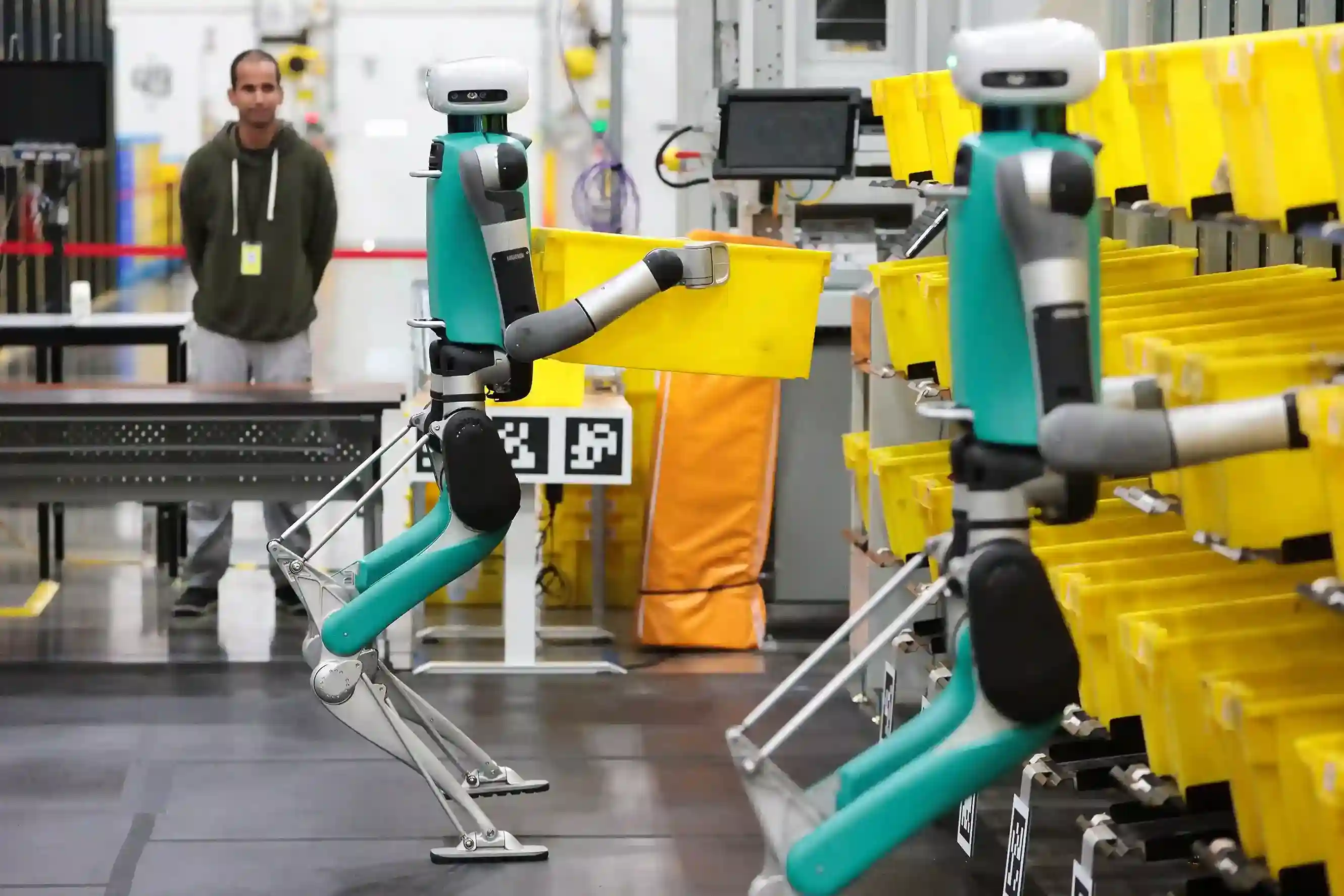 Amazon warehouse robots moving and sorting yellow bins inside a fulfillment center.