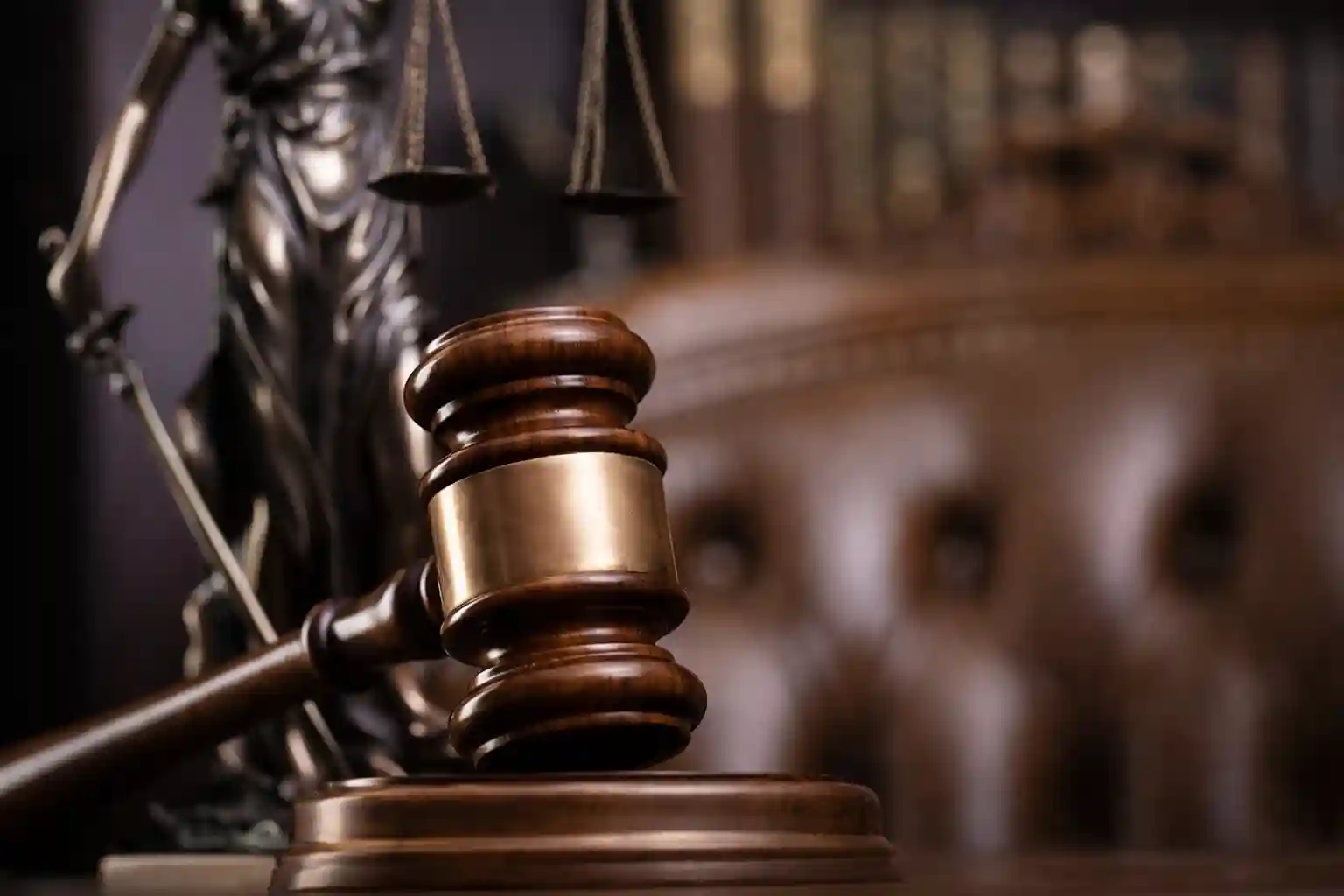 Close-up of a gavel and scales of justice, symbolizing law and court proceedings, with a blurred background of legal books