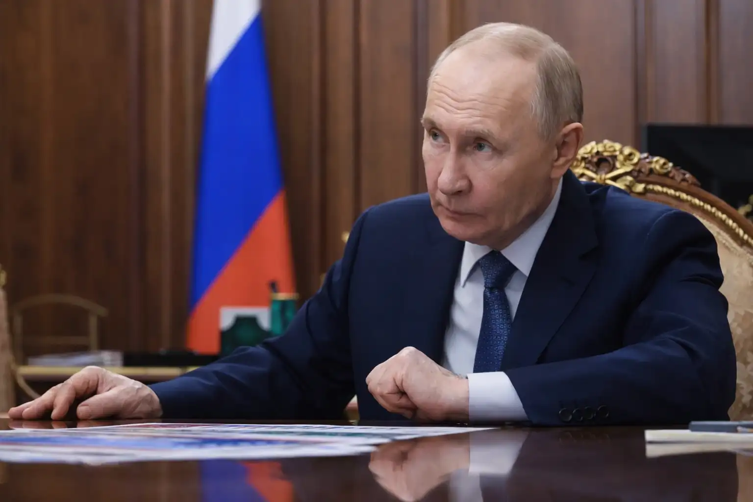 Russian President Vladimir Putin sitting at a desk in a formal meeting, discussing military strategy during the ongoing Ukraine conflict.