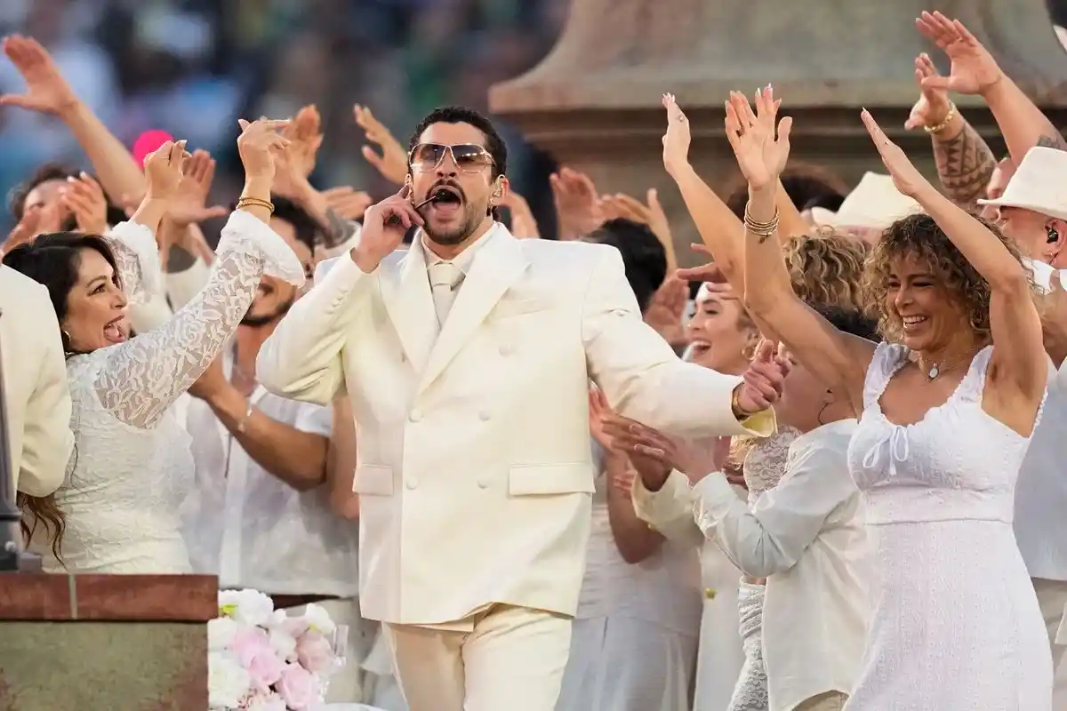Bad Bunny performing at the Super Bowl 60 halftime show, leading a group of dancers in white attire.