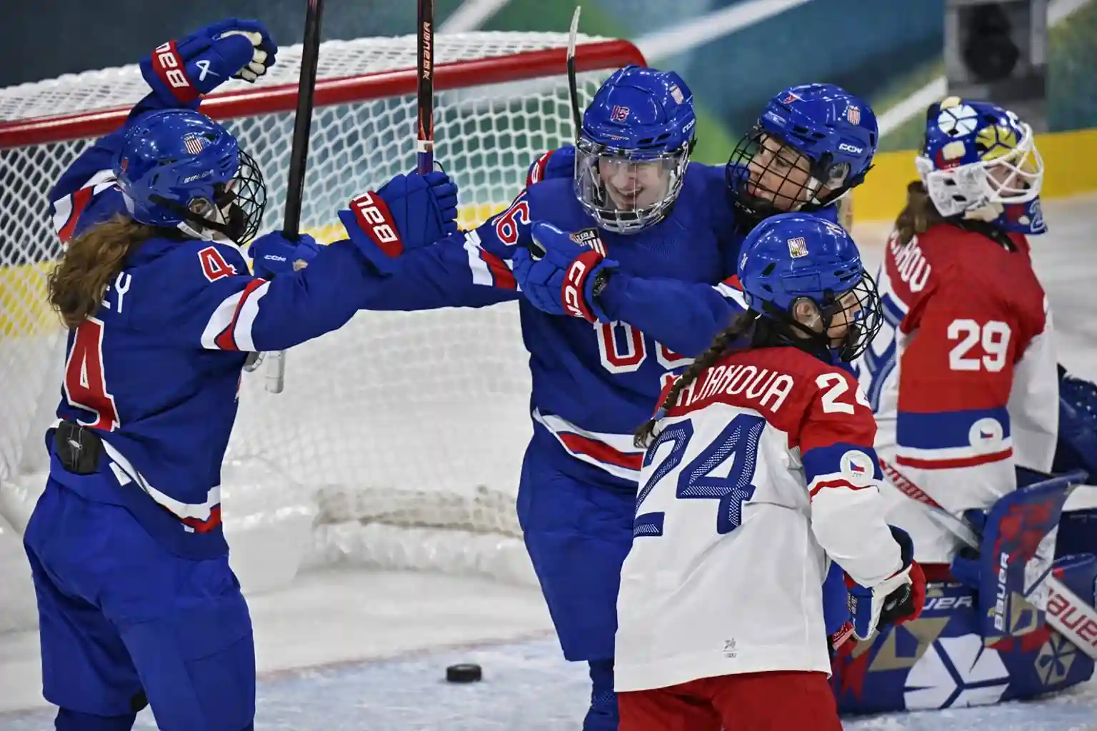 Team USA women’s hockey players celebrate a goal in front of the net against Czechia during the Milano Cortina 2026 Olympic opener